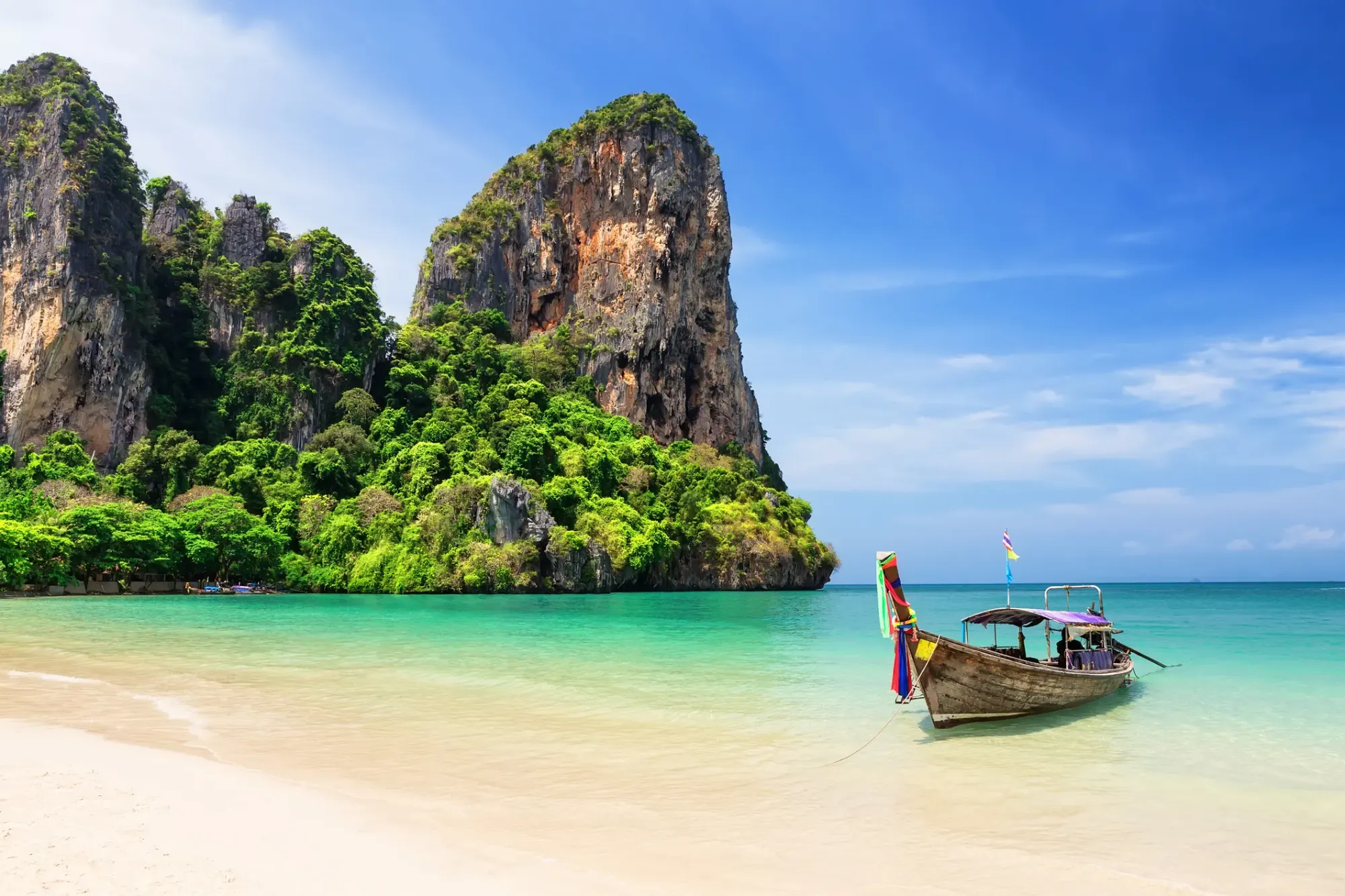A longtail boat moored off Railay Beach, Krabi, with limestone cliffs behind